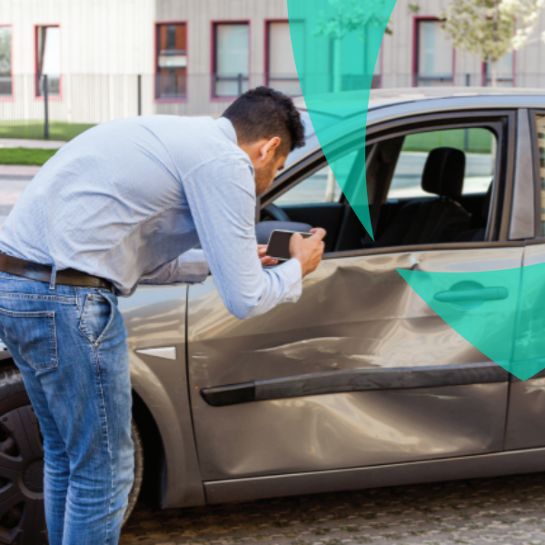 Man taking photo of car damage representing liability claims and accident assessment by Van Ameyde