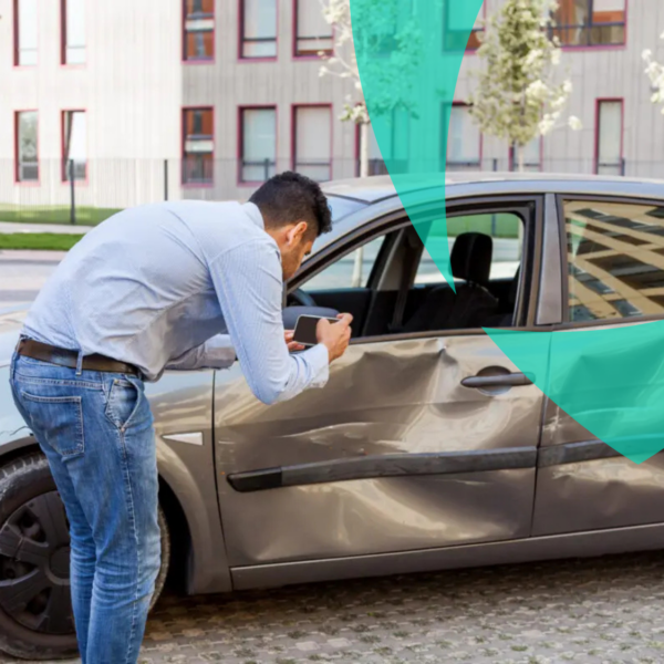 Hombre tomando fotos de un coche dañado para la evaluación del seguro de automóvil