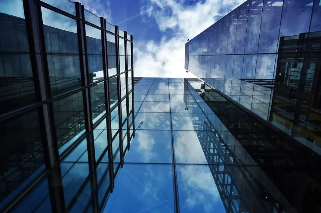 Des immeubles de bureaux modernes en verre reflétant le ciel, symbolisant la transparence et le contrôle dans les services de gestion des sinistres auto-assurés et captifs de Van Ameyde.