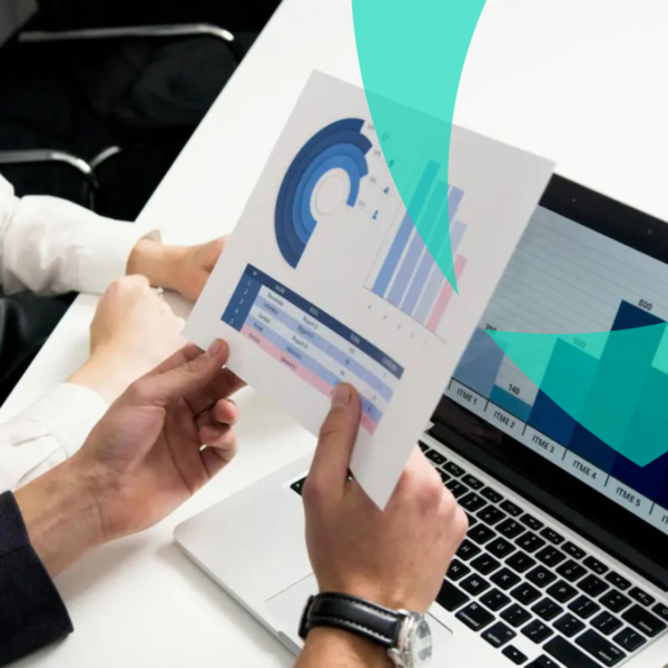 Analistas de risco analisam gráficos de dados financeiros e operacionais em papel e computador portátil durante a avaliação.