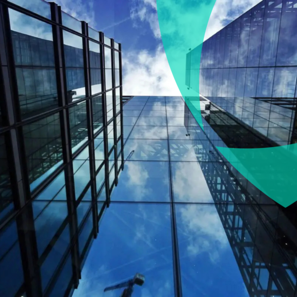 Edifícios modernos de escritórios em vidro que refletem o céu, simbolizando transparência e controlo nos serviços de gestão de sinistros auto-segurados e cativos da Van Ameyde.