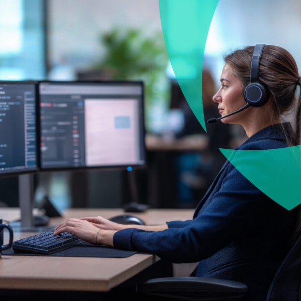 Van Ameyde specialist working on dual monitors with a headset, representing digital and sustainable claims handling.